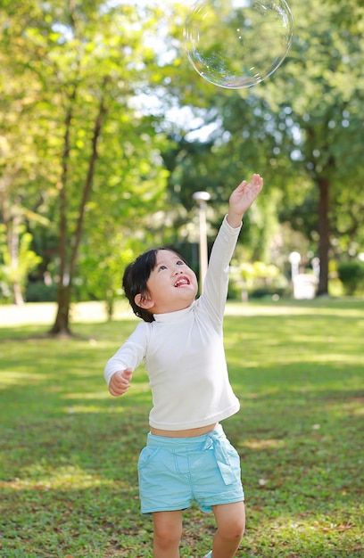 Menina bonitinha jogando bolha no parque.