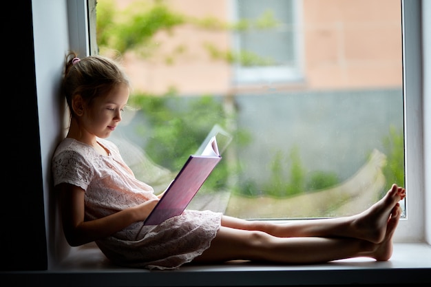 Menina bonitinha lendo livro em casa