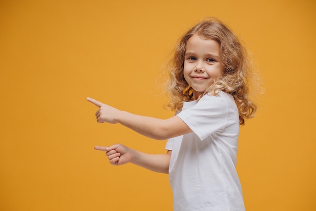 Menina bonitinha mostrando emoções, isolada em fundo amarelo