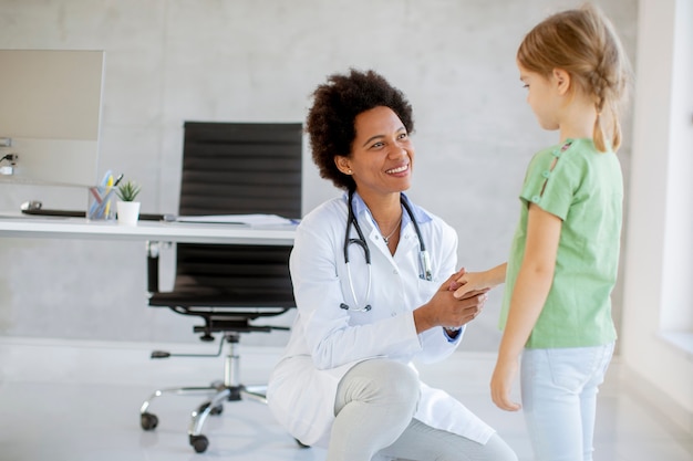 Foto menina bonitinha no exame do pediatra pela médica afro-americana