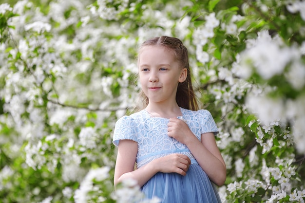 Menina bonitinha no jardim de macieira florescendo na primavera