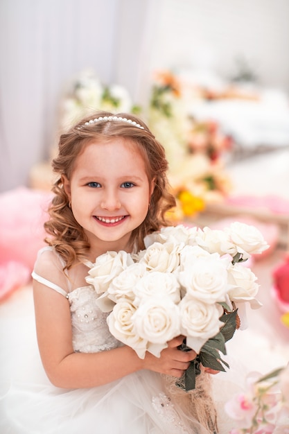 Menina bonitinha num lindo vestido com cabelo ondulado e buquê