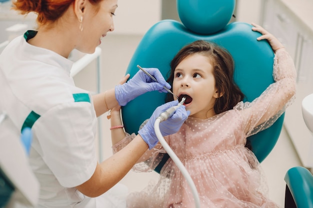 Foto menina bonitinha olhando para o médico enquanto fazia cirurgia nos dentes em estomatologia pediátrica.