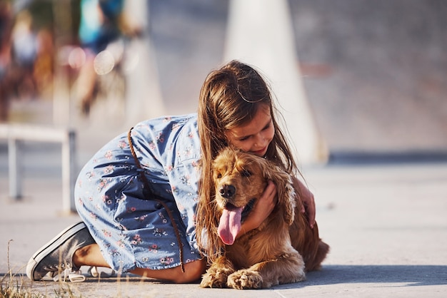 Menina bonitinha passeando com o cachorro ao ar livre em dia de sol