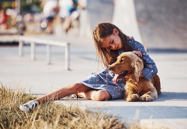 Menina bonitinha passeando com o cachorro ao ar livre em dia de sol