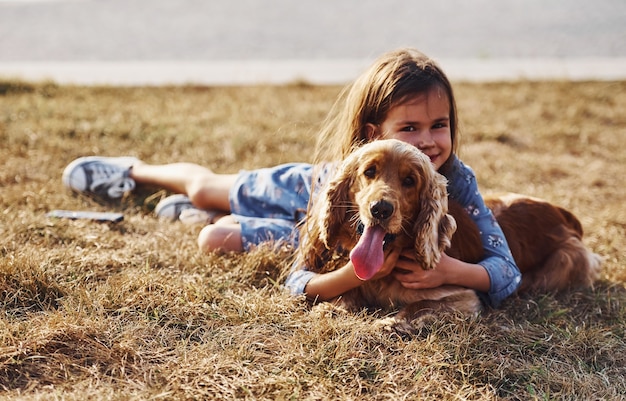 Menina bonitinha passeando com o cachorro ao ar livre em dia de sol