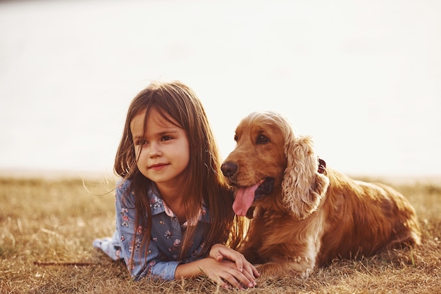 Menina bonitinha passeando com o cachorro ao ar livre em dia de sol