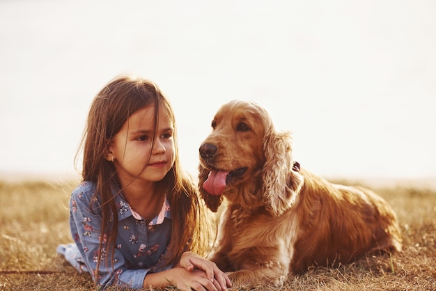 Menina bonitinha passeando com o cachorro ao ar livre em dia de sol