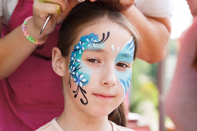 Menina bonitinha recebendo uma pintura no rosto