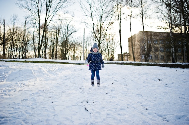 Menina bonitinha se divertindo ao ar livre num dia de inverno.