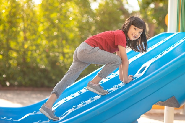 Menina bonitinha se divertindo em um playground ao ar livre no verão