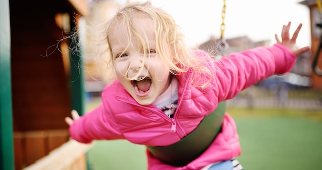 Menina bonitinha se divertindo no playground ao ar livre