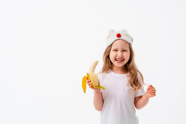 Menina bonitinha segurando banana na mão isolada