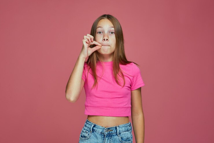Foto menina bonitinha segurando o dedo nos lábios, símbolo do gesto silencioso de pedir para ficar quieto, silêncio