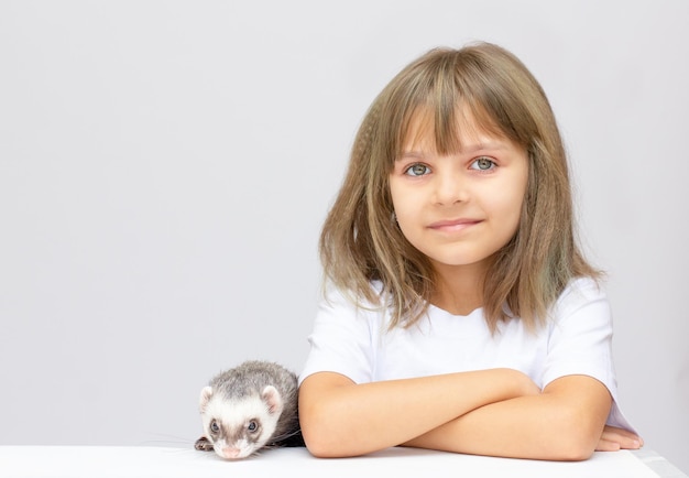 Menina bonitinha segurando um animal de estimação furão. Isolado em pbackground.