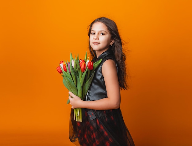 Menina bonitinha segurando um buquê de tulipas em um fundo amarelo Feliz dia das mulheres Lugar para texto Emoções vívidas 8 de março