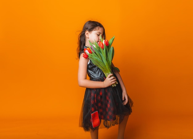 Menina bonitinha segurando um buquê de tulipas em um fundo amarelo Feliz dia das mulheres Lugar para texto Emoções vívidas 8 de março