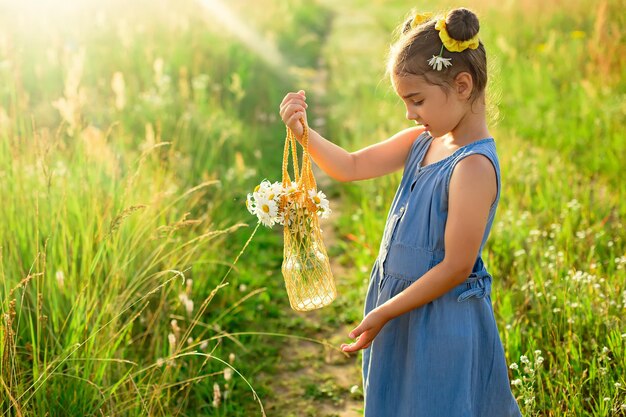 Menina bonitinha segurando um saco de malha com um buquê de margaridas