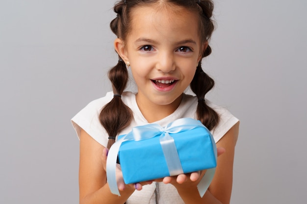 Foto menina bonitinha segurando uma caixa de presente azul nas mãos