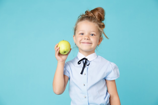 Menina bonitinha segurando uma maçã isolada sobre o fundo azul