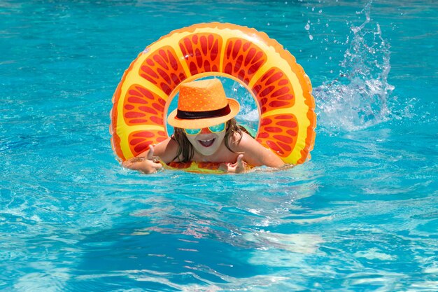 Menina bonitinha sorridente em óculos de sol e chapéu de verão na piscina em dia de sol criança na piscina swimmi
