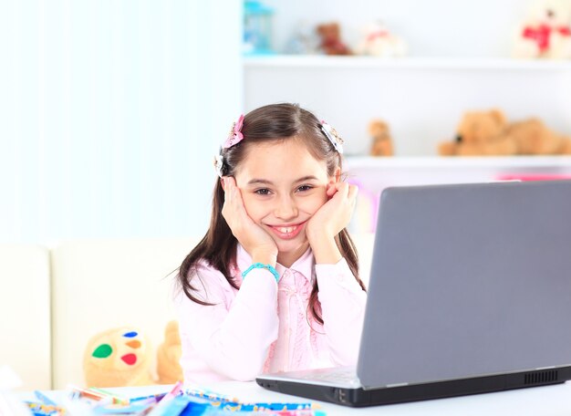 Menina bonitinha sorrindo e olhando para o laptop, menina usando laptop