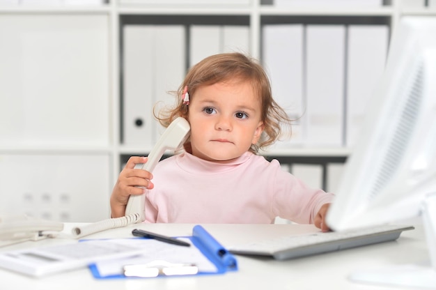 Menina bonitinha usando telefone no escritório