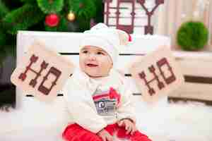 Foto menina bonitinha vestida como flocos de neve perto da árvore de natal e decorações