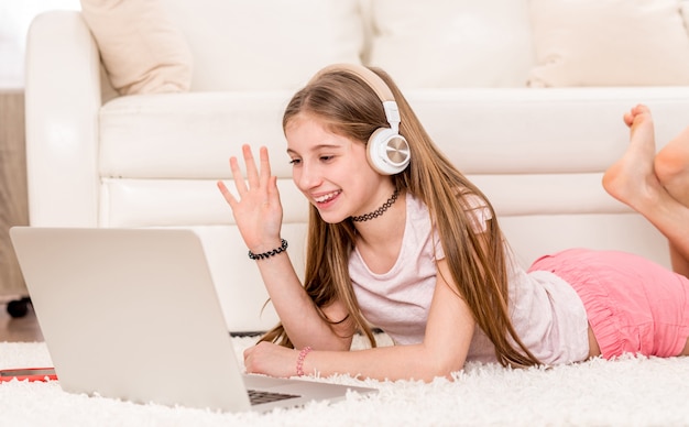 Menina bonito adolescente sorrindo para seu laptop