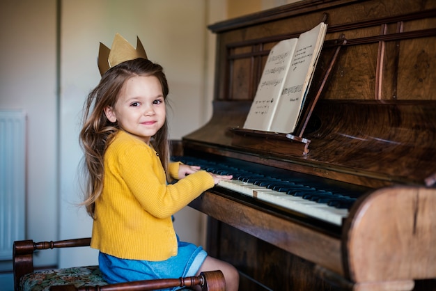 Menina bonito adorável que joga o conceito do piano