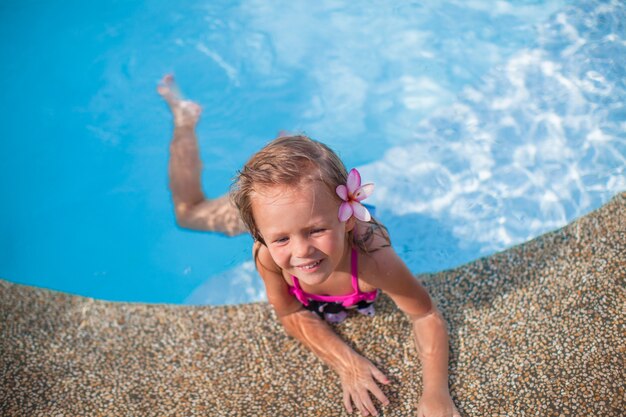 Menina bonito com flor atrás da orelha na piscina