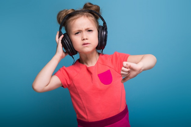 Menina bonito no vestido rosa e fones de ouvido