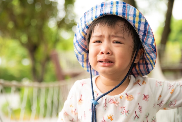 Menina bonito pequena triste que grita no jardim.