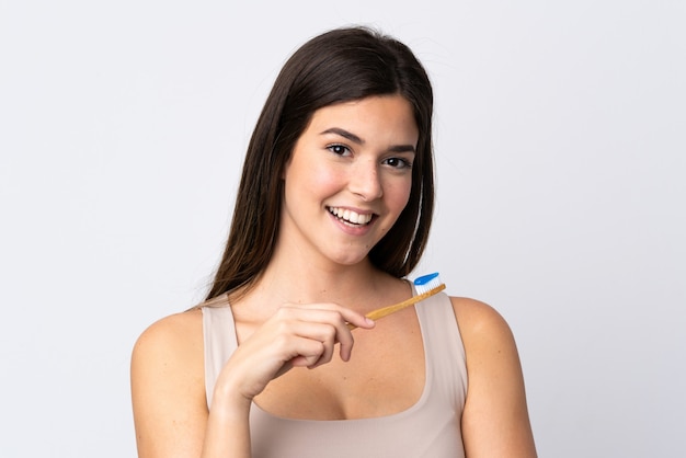 Menina brasileira adolescente escovando os dentes sobre parede branca isolada