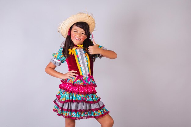 Foto menina brasileira com roupas de festa junina como com os dedos