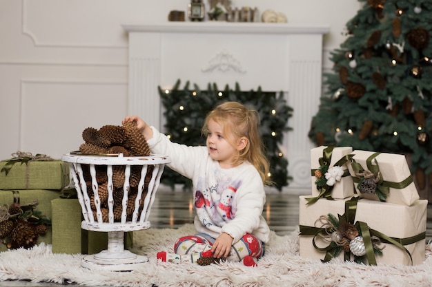 Menina brinca com decorações de pinhas para a árvore de Natal