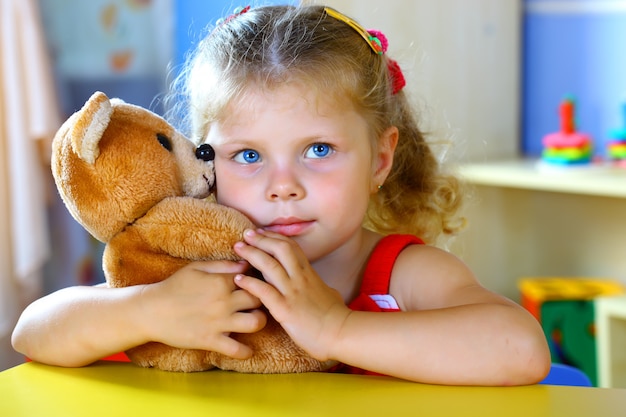 Menina brinca com um ursinho de pelúcia