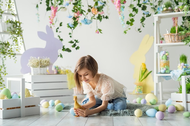 Menina brinca e se comunica com patinho enquanto se senta no chão decoração de páscoa