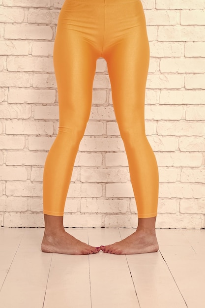 Menina brincalhona em uma posição de dança louca de balé dos pés mulher em leggings laranja nas pernas Dance ao ritmo do seu coração laranja praticando no estúdio de balé esporte desgaste moda Fit For Every Style