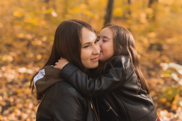 Menina brincando com a mãe no parque de outono