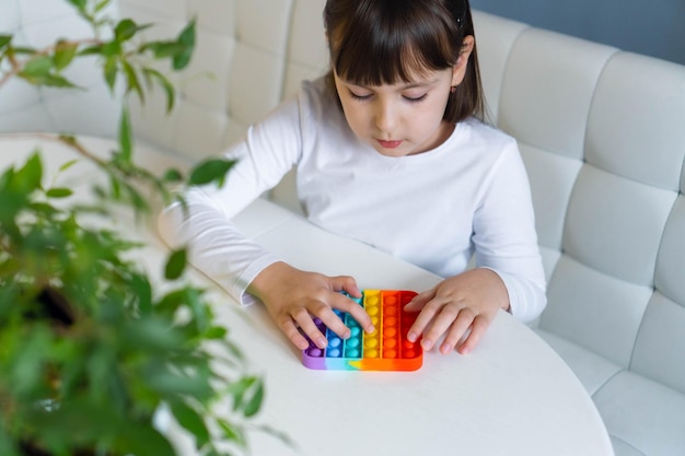 Menina brincando com arco-íris pop it fidget o conceito de brinquedo popit de saúde mental