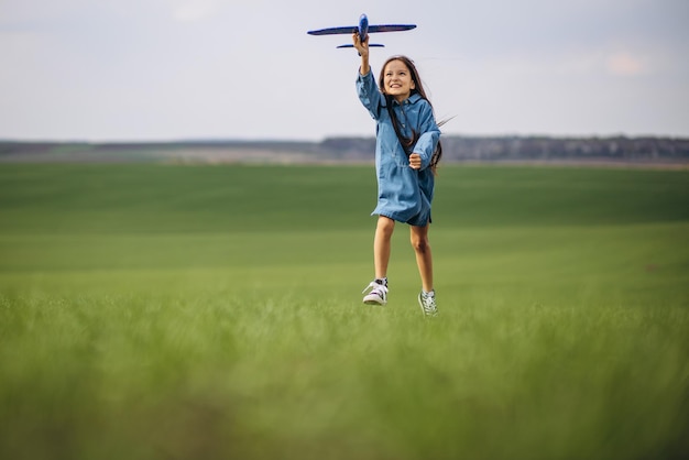 Menina brincando com avião de brinquedo no campo