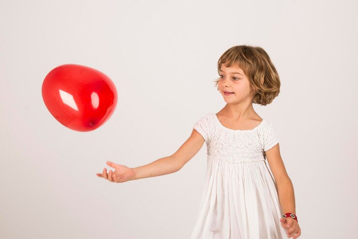 Foto menina brincando com balão vermelho contra fundo branco