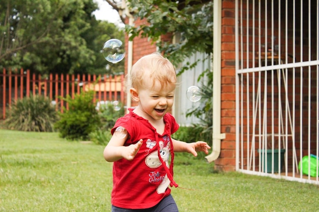 Menina brincando com bolhas no gramado