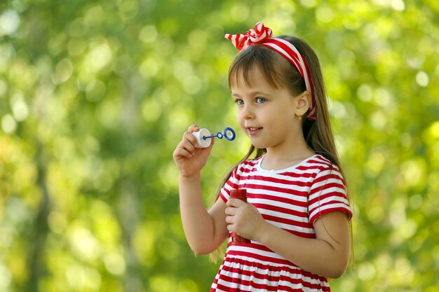 Menina brincando com bolhas no parque