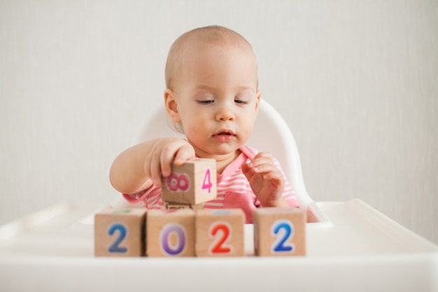 Menina brincando com cubos de madeira com números brilhantes 2022