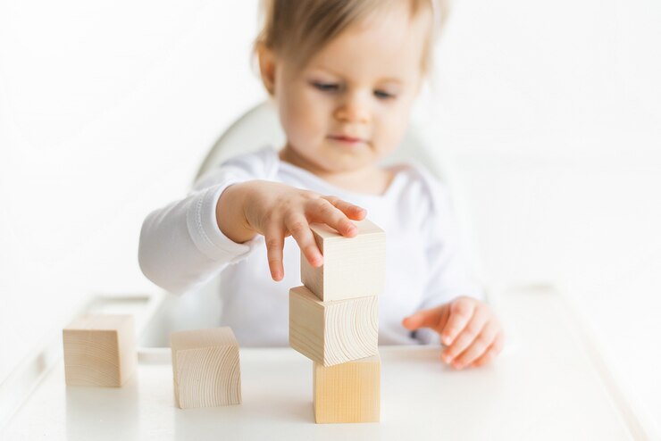 Foto menina brincando com cubos de madeira pela mão esquerda. jogando a criança isolada no fundo branco. jogos para crianças, educação pré-escolar. feche acima, foco seletivo