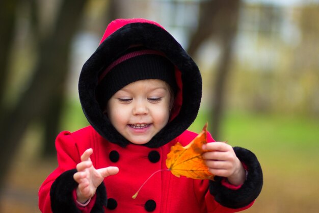 Menina brincando com folha amarela no parque outono