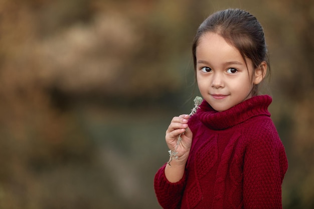 Menina brincando com folhas caídas de outono