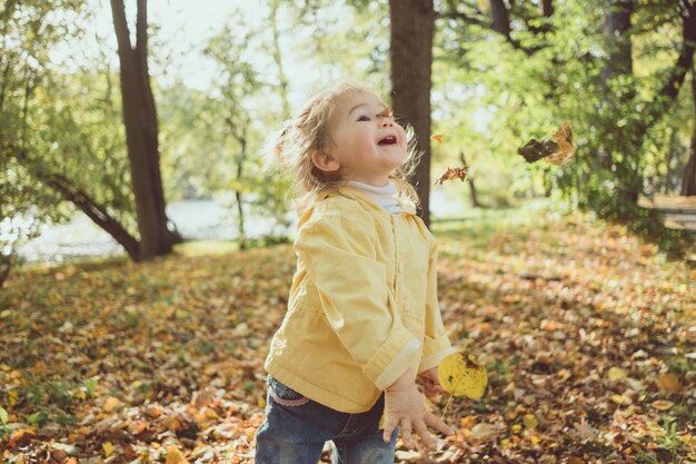 Menina brincando com folhas no parque no outono close-up